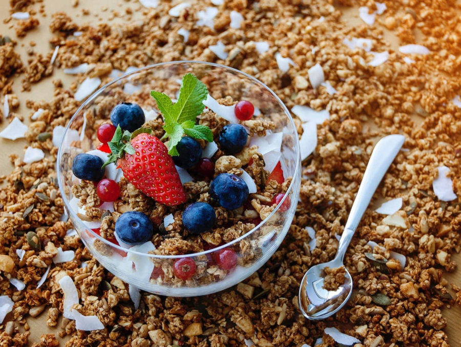 A bowl of granola topped with fresh berries and sprinkled with coconut flakes, showcasing a colorful and nutritious breakfast option.